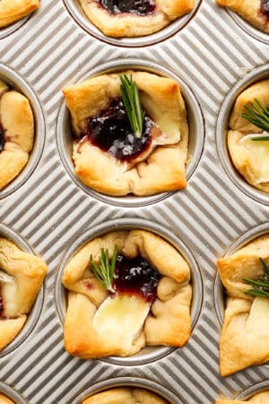 Top down shot of a muffin pan filled with baked brie bites.