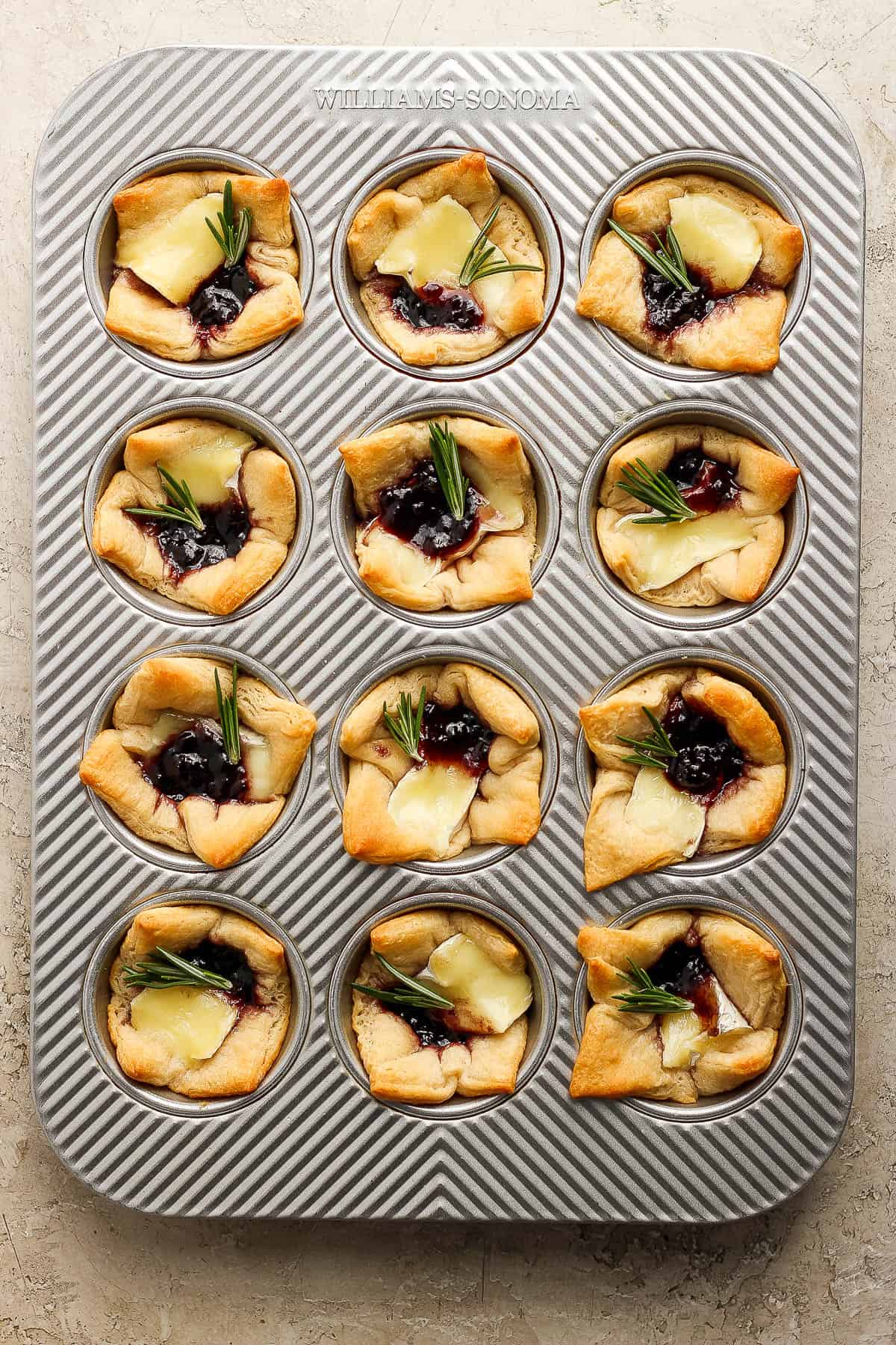 Cooked baked brie bites in muffin tray.