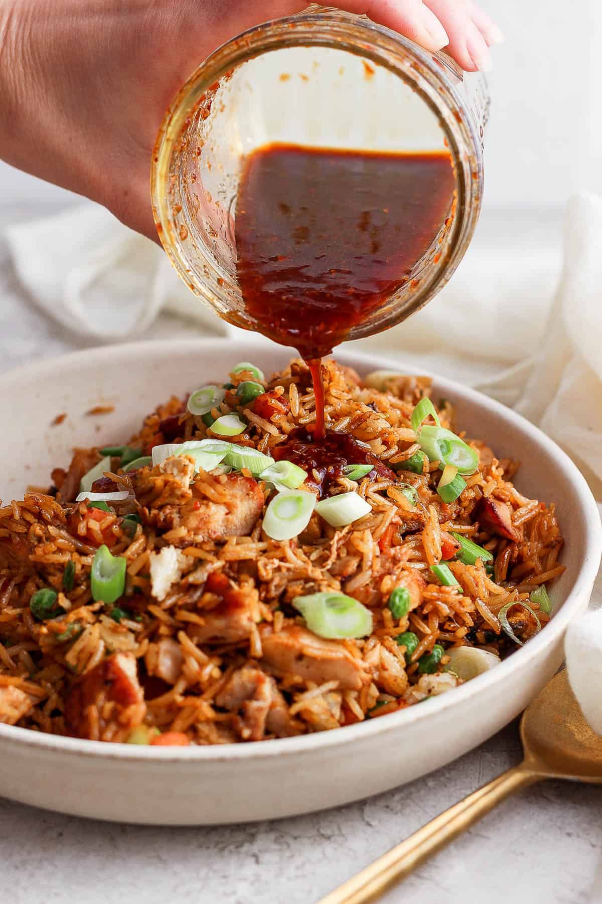 Fried rice sauce being poured over chicken fried rice.