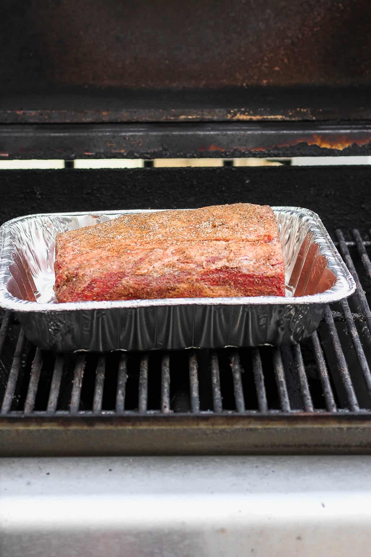 A seasoned prime rib in a foil basket on the grill.