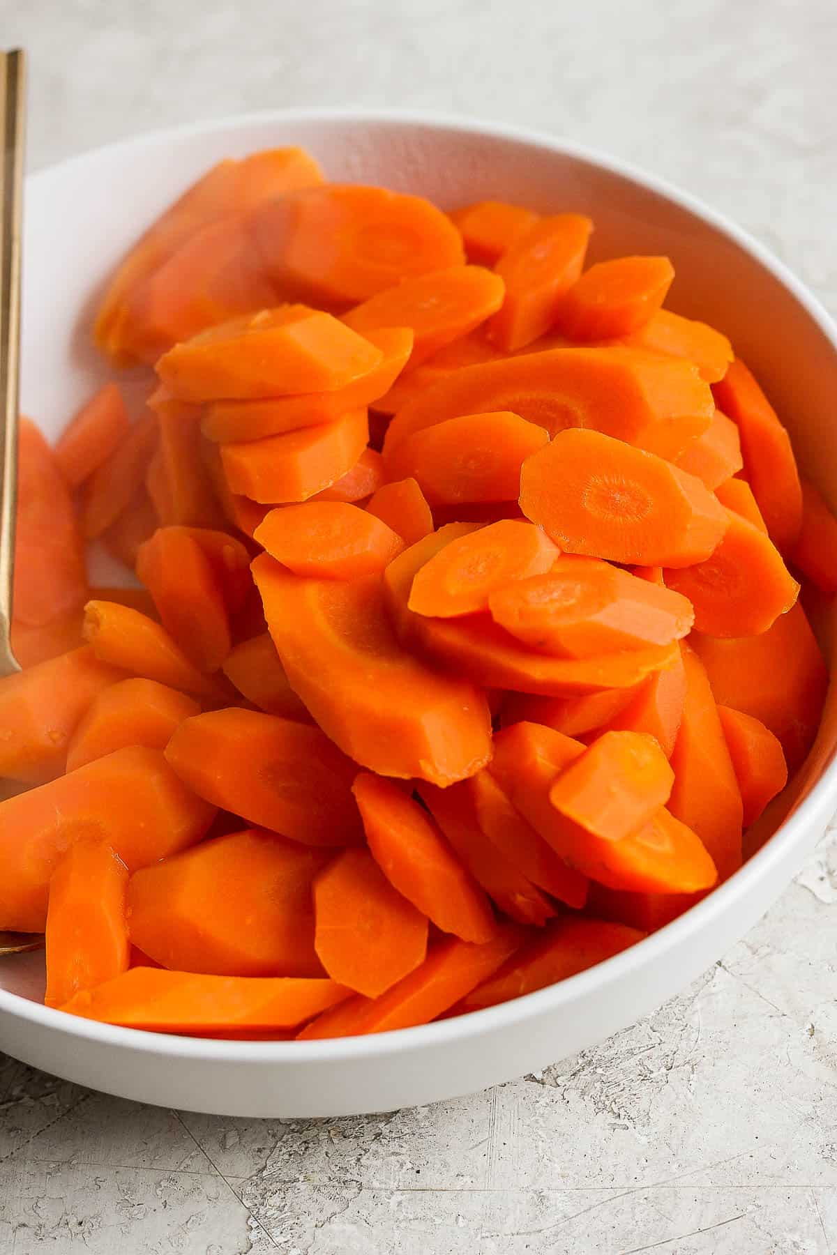 Boiled carrots in a white bowl.