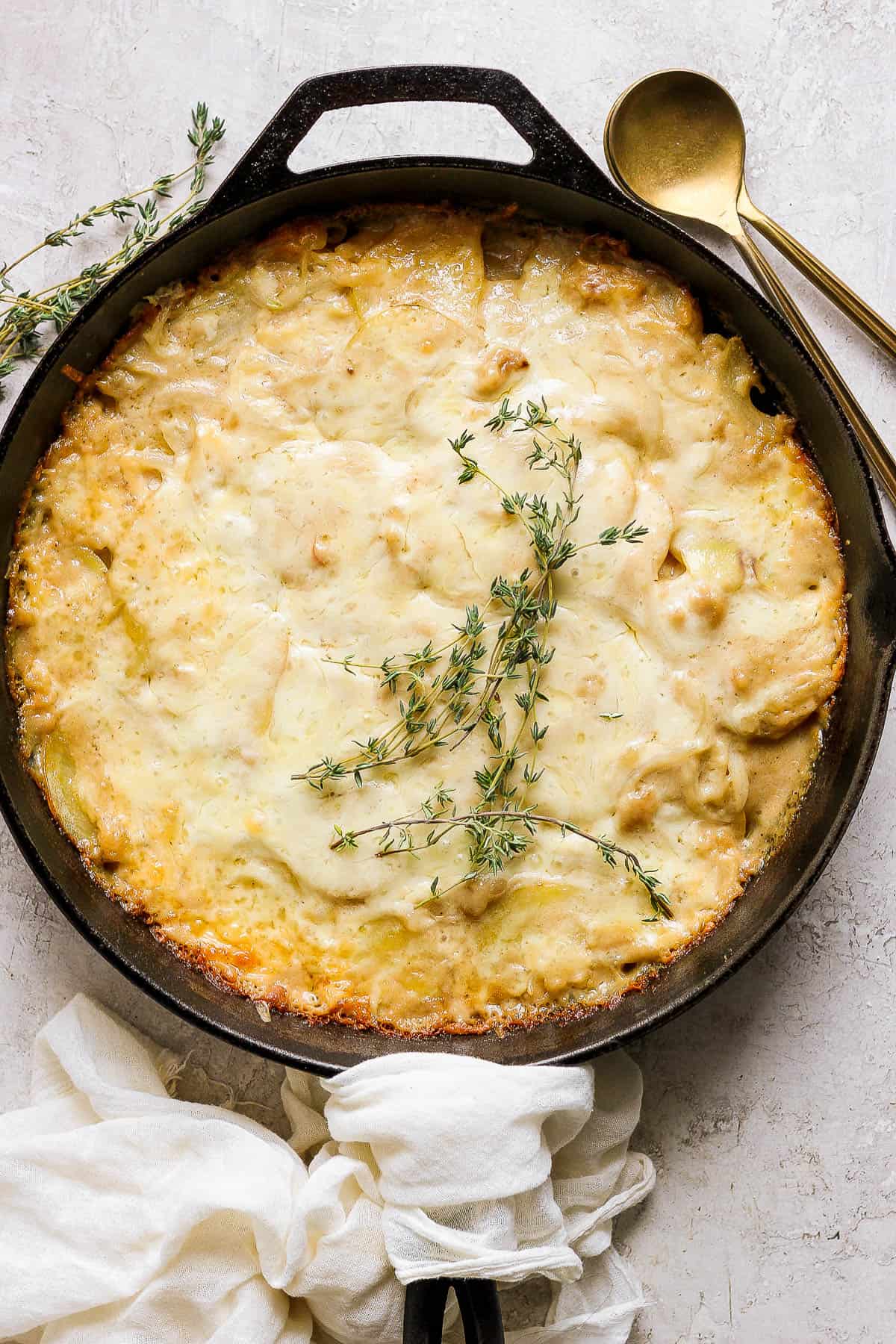 Fully baked potatoes au gratin in a cast iron skillet.