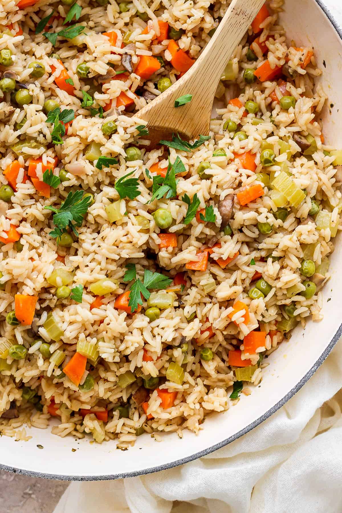 Fully cooked rice pilaf in a braiser with a wooden spoon.
