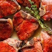 A plate of smoked lamb chops on a plate with fresh thyme.