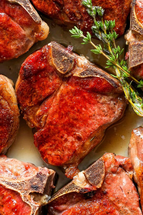 A plate of smoked lamb chops on a plate with fresh thyme.