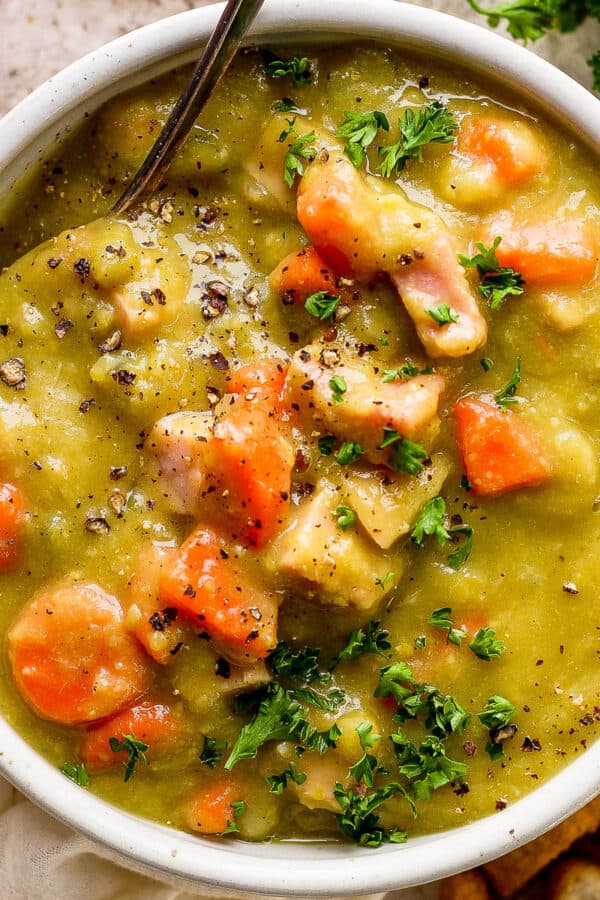 Top down shot of bowl of split pea soup with ham and a spoon sticking out.