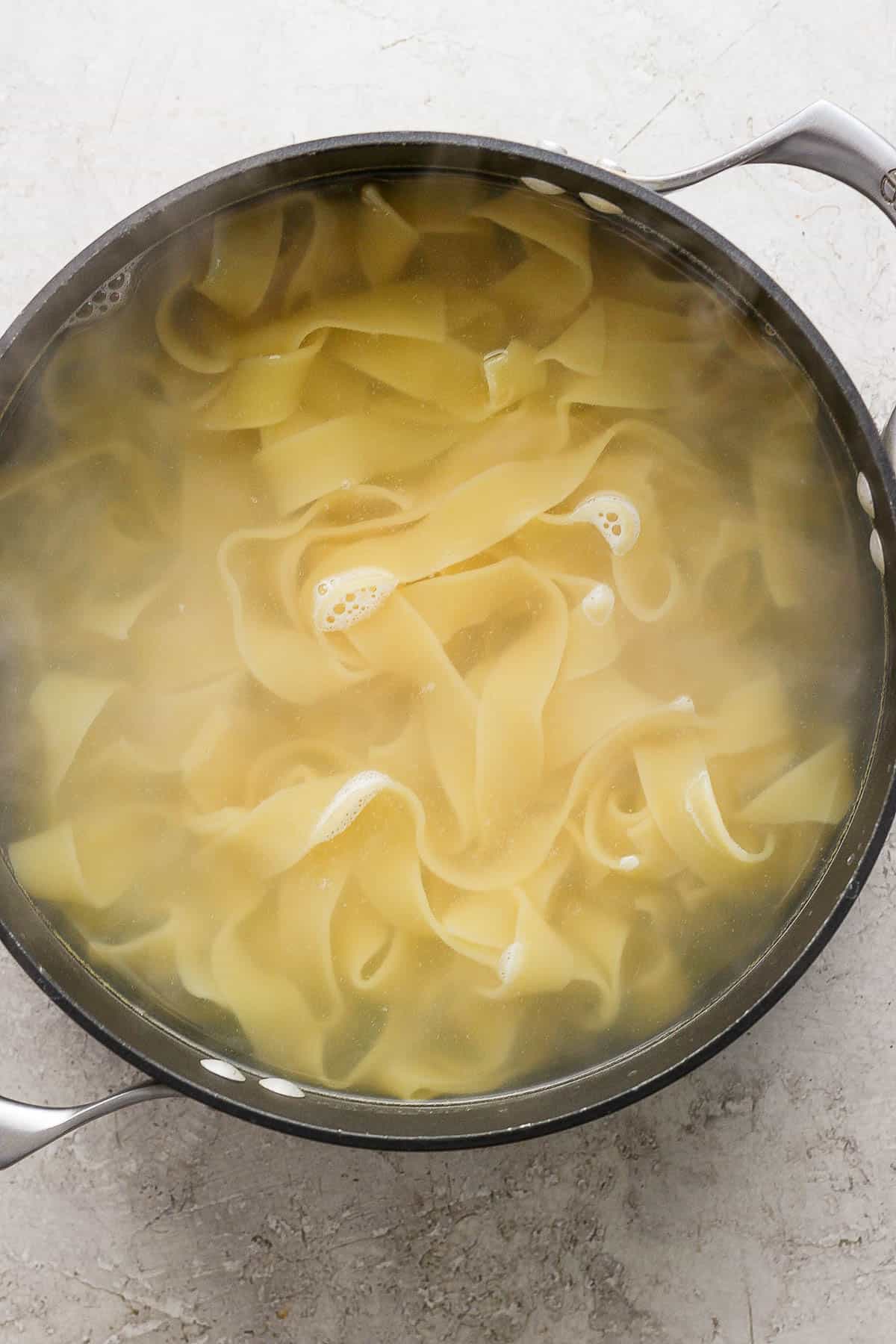 Pappardelle pasta boiling in a large pot.