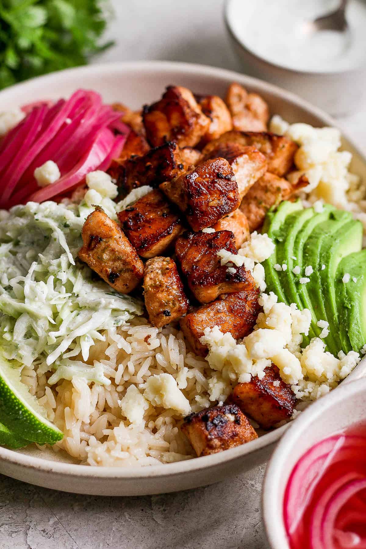 A close-up shot of perfectly cooked salmon bites on a salmon taco bowl.