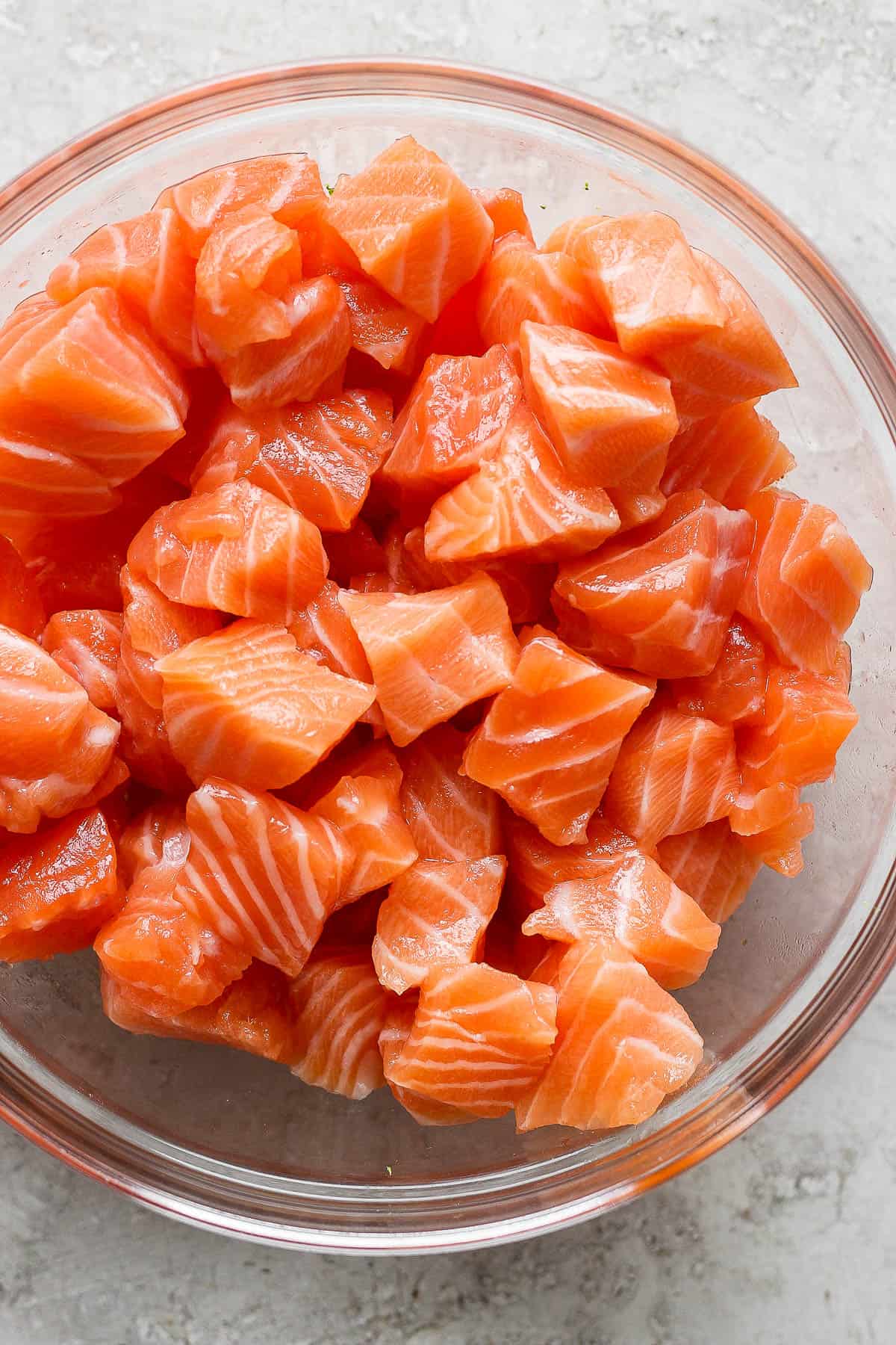 Cubed fresh salmon in a glass bowl.