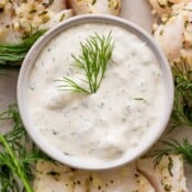Top down shot of a bowl of homemade tartar sauce next to a few pieces of baked cod.