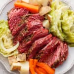 Top down shot of a platter with sliced corned beef, carrots, potatoes and cabbage.
