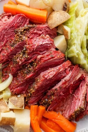 Top down shot of a platter with sliced corned beef, carrots, potatoes and cabbage.
