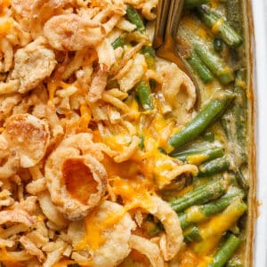 Close up shot of a pan of cheesy green bean casserole with a spoon sticking out.