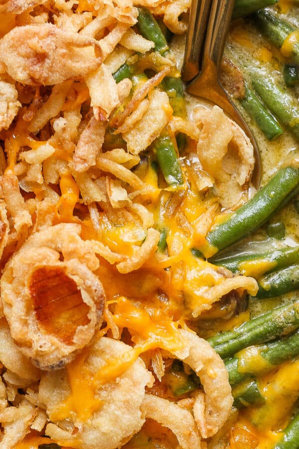 Close up shot of a pan of cheesy green bean casserole with a spoon sticking out.