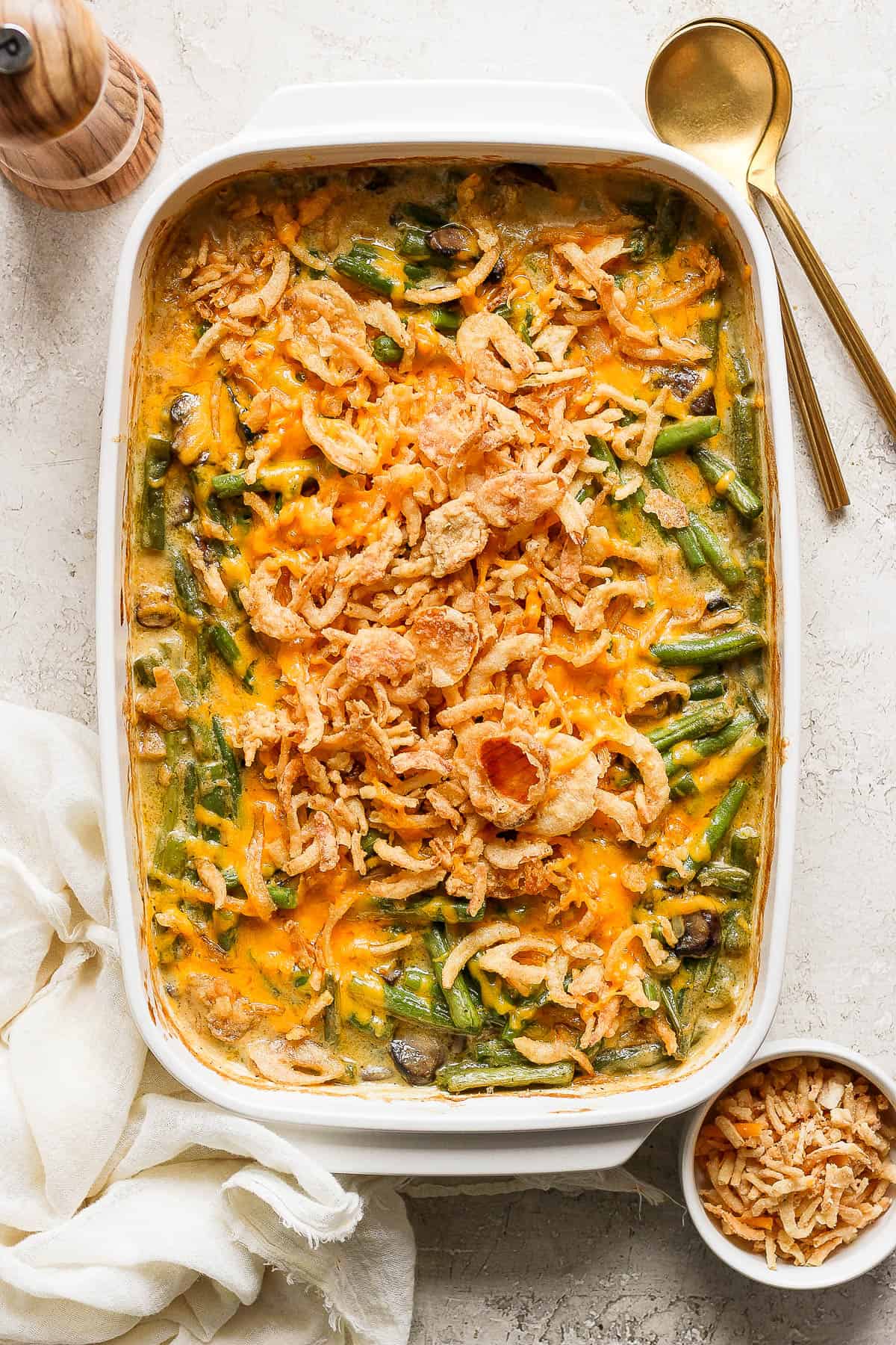 A fully baked cheesy green bean casserole with french fried onions on top.