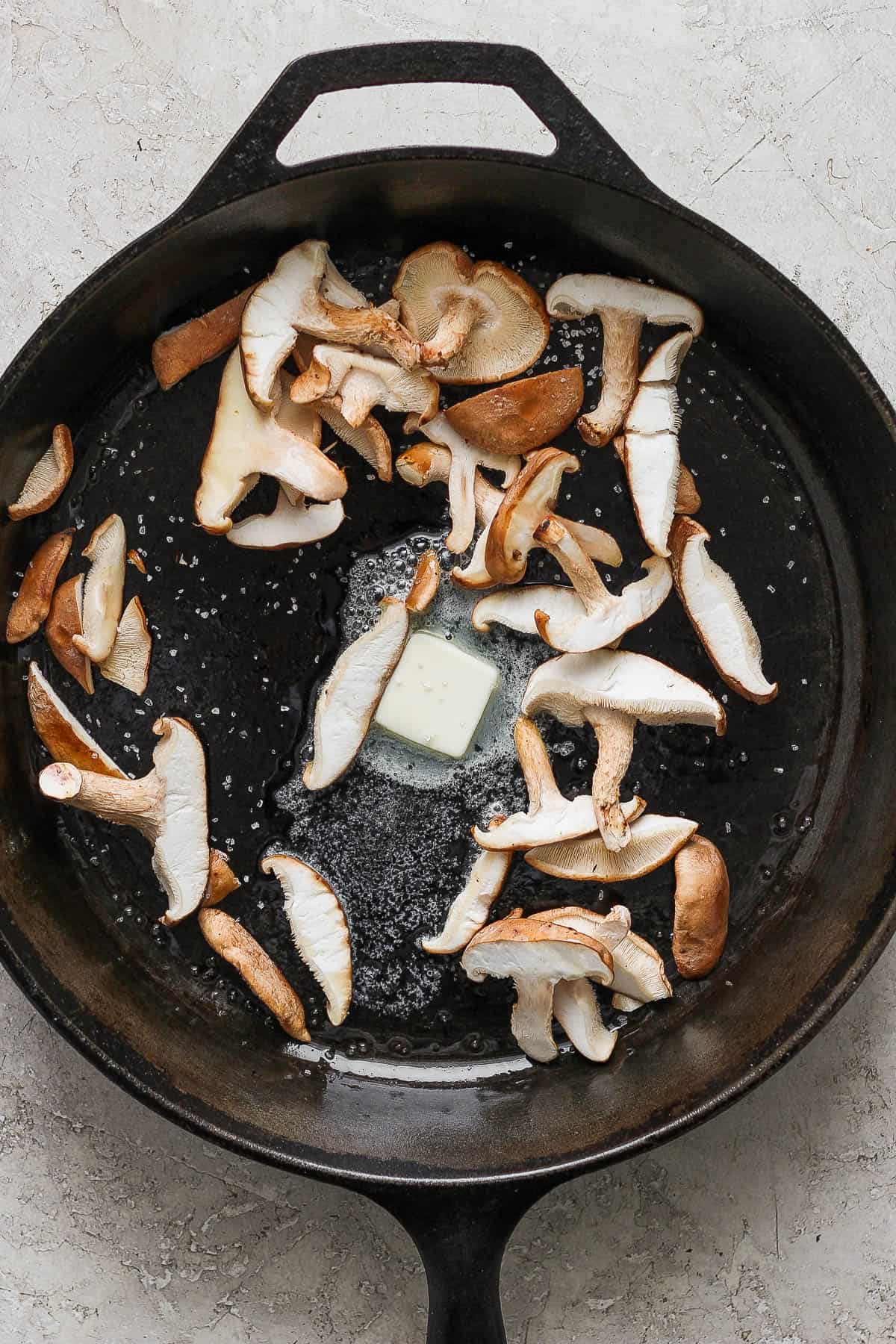 Shiitake mushrooms in a cast iron skillet with melted butter and salt.