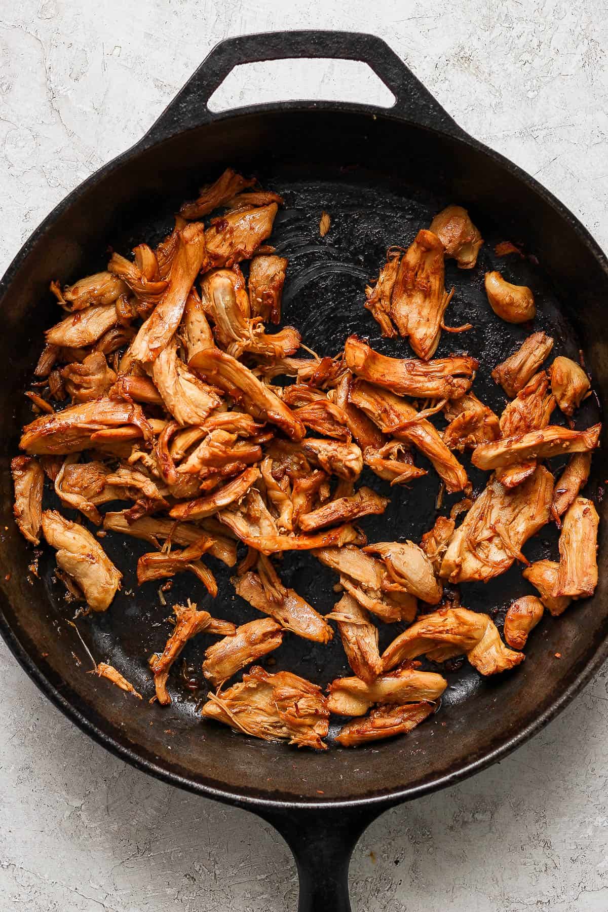 Mushrooms removed from the pan and shredded chicken has been added with some soy sauce, rice wine vinegar, and chili garlic sauce.