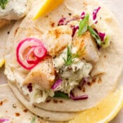 Top down shot of a cod taco with fresh tartar sauce, dill and quick pickled onions.