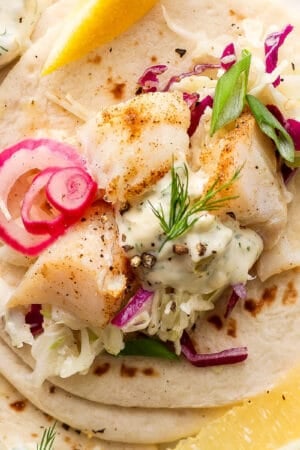 Top down shot of a cod taco with fresh tartar sauce, dill and quick pickled onions.