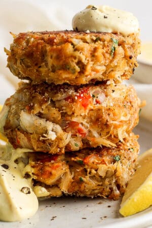 Straight on shot of 3 crab cakes stacked with sauce on top.