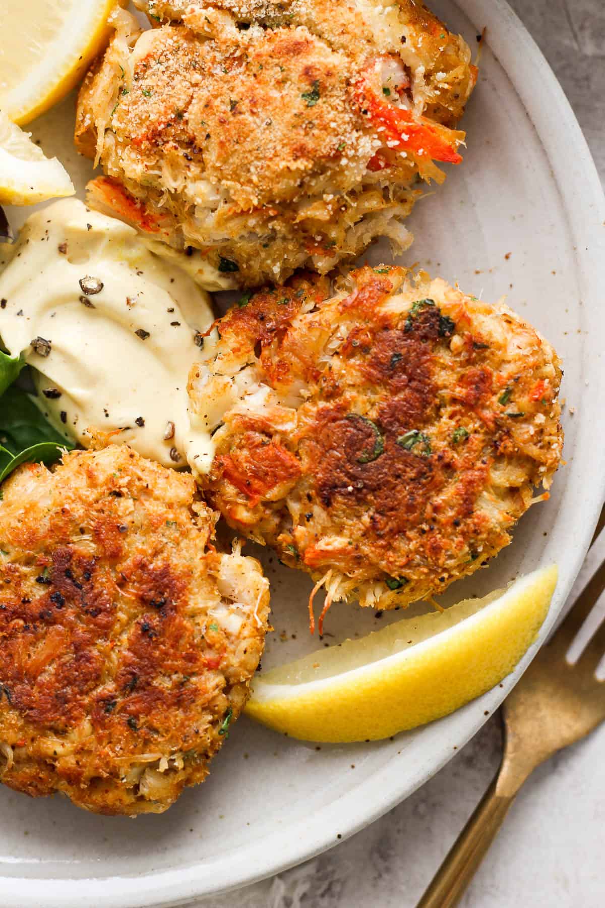 Close-up shot of three crab cakes on a plate.