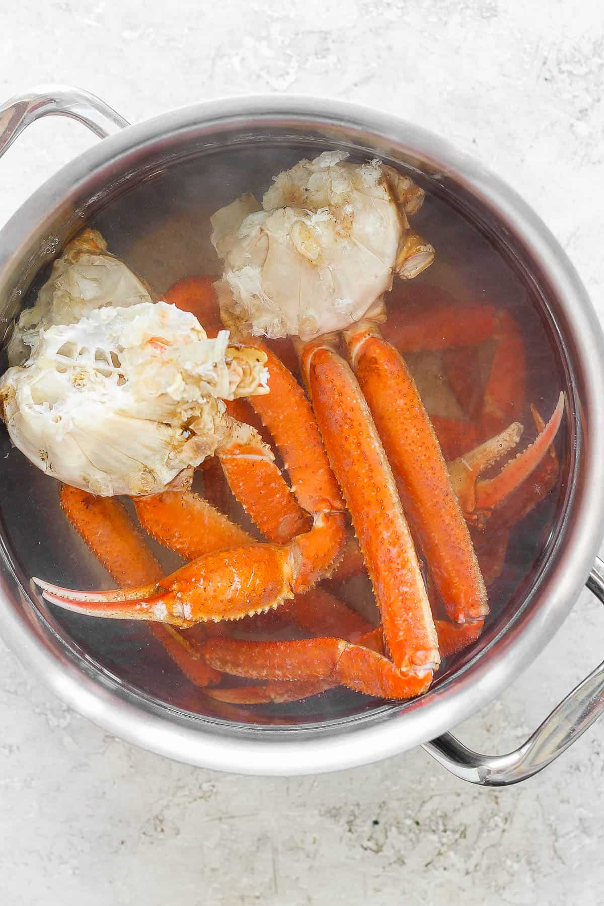 Crab leg clusters boiling in a pot of water.