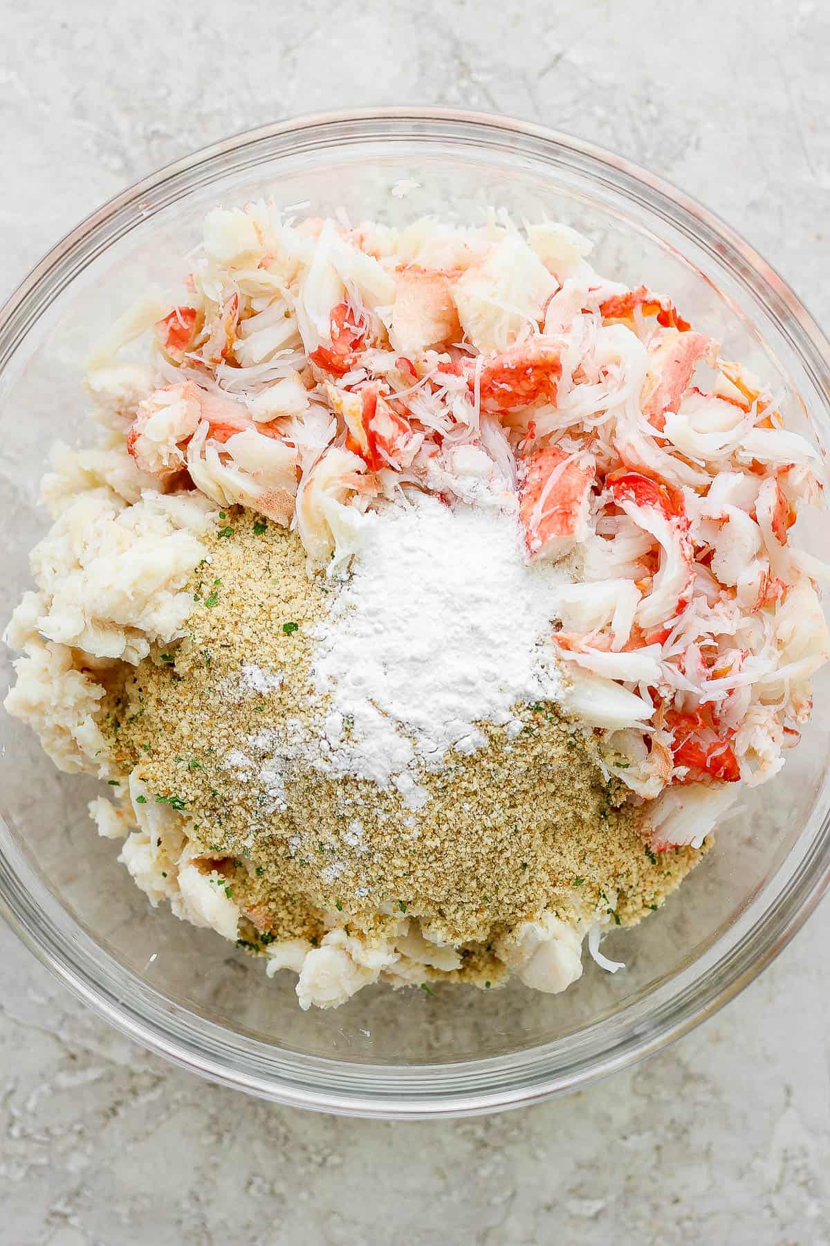Crab leg meat, lump crab meat, and breadcrumbs in a glass bowl.