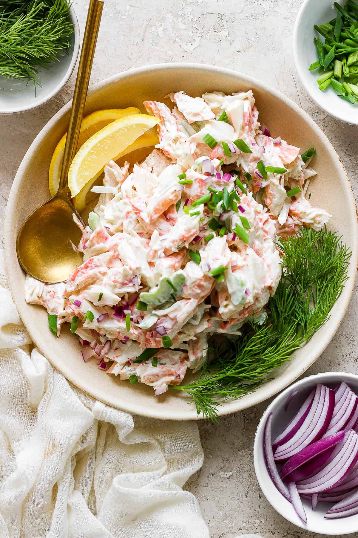 Crab salad in a shallow bowl with lemon wedges and fresh dill.
