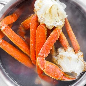 Top down shot of boiled crab legs in a pot of water.