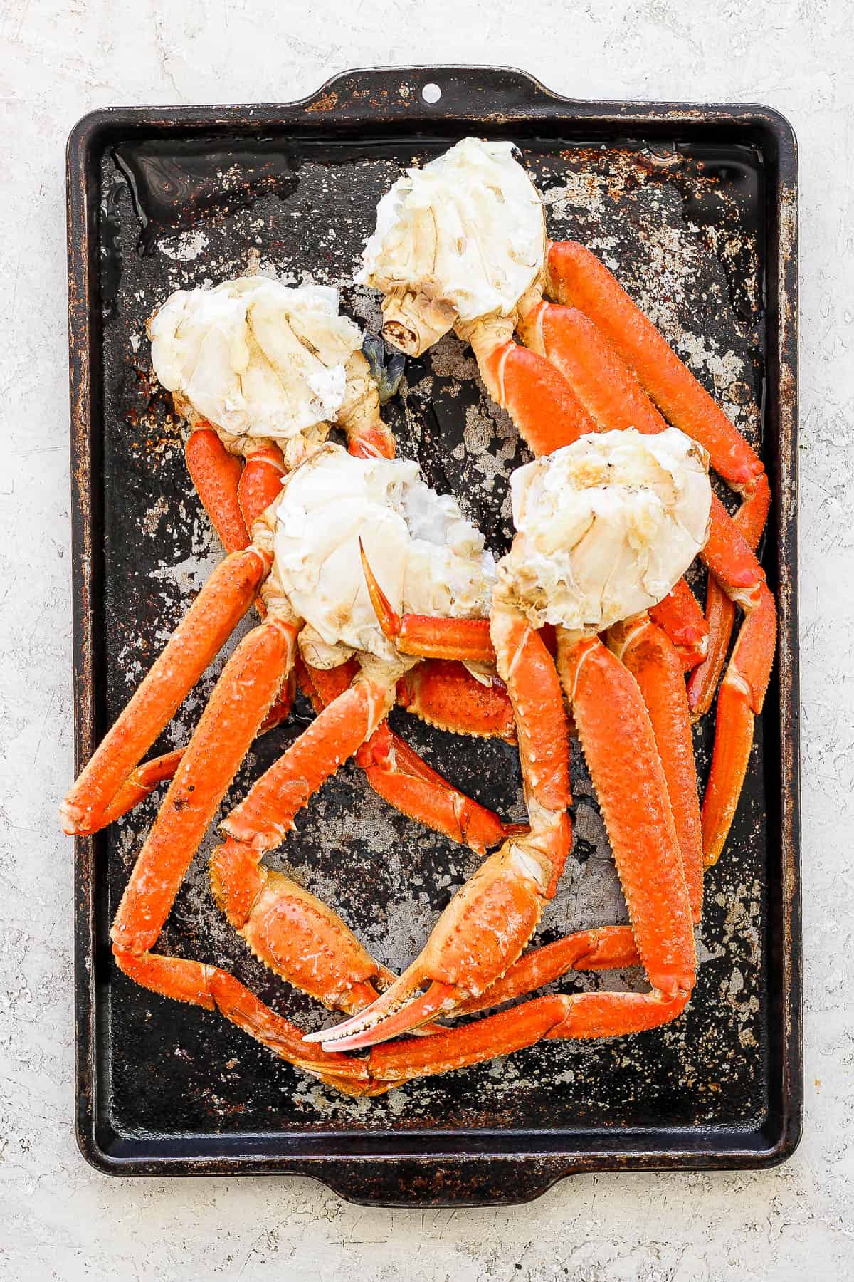 Boiled crab legs on a baking sheet after cooking.