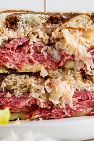 Straight on shot of a reuben sandwich cut in half and then stacked on top of each other.