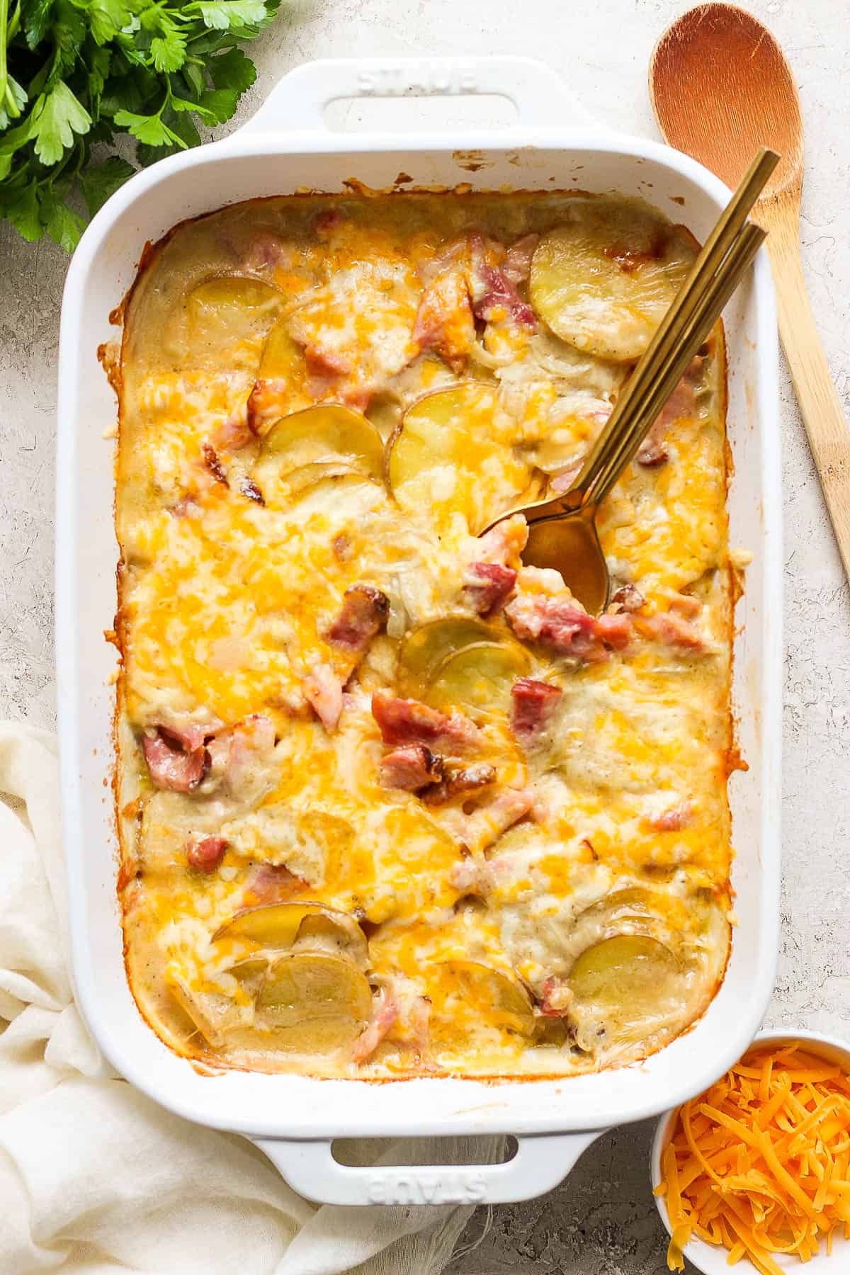 Scalloped potatoes and ham fully cooked in a white baking dish.