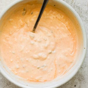 Top down shot of a bowl of homemade thousand island dressing with a spoon sticking out.