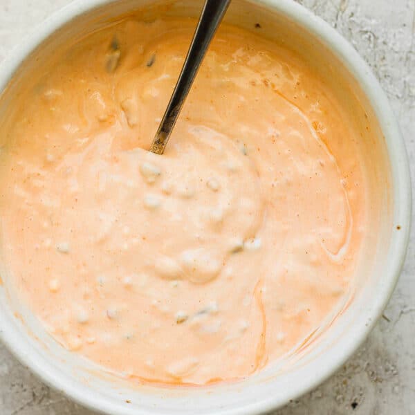 Top down shot of a bowl of homemade thousand island dressing with a spoon sticking out.