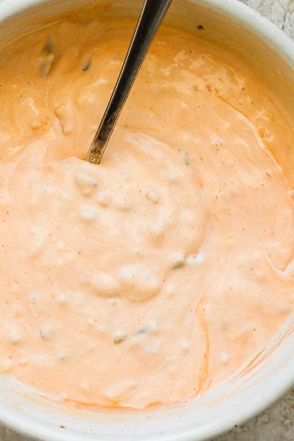 Top down shot of a bowl of homemade thousand island dressing with a spoon sticking out.