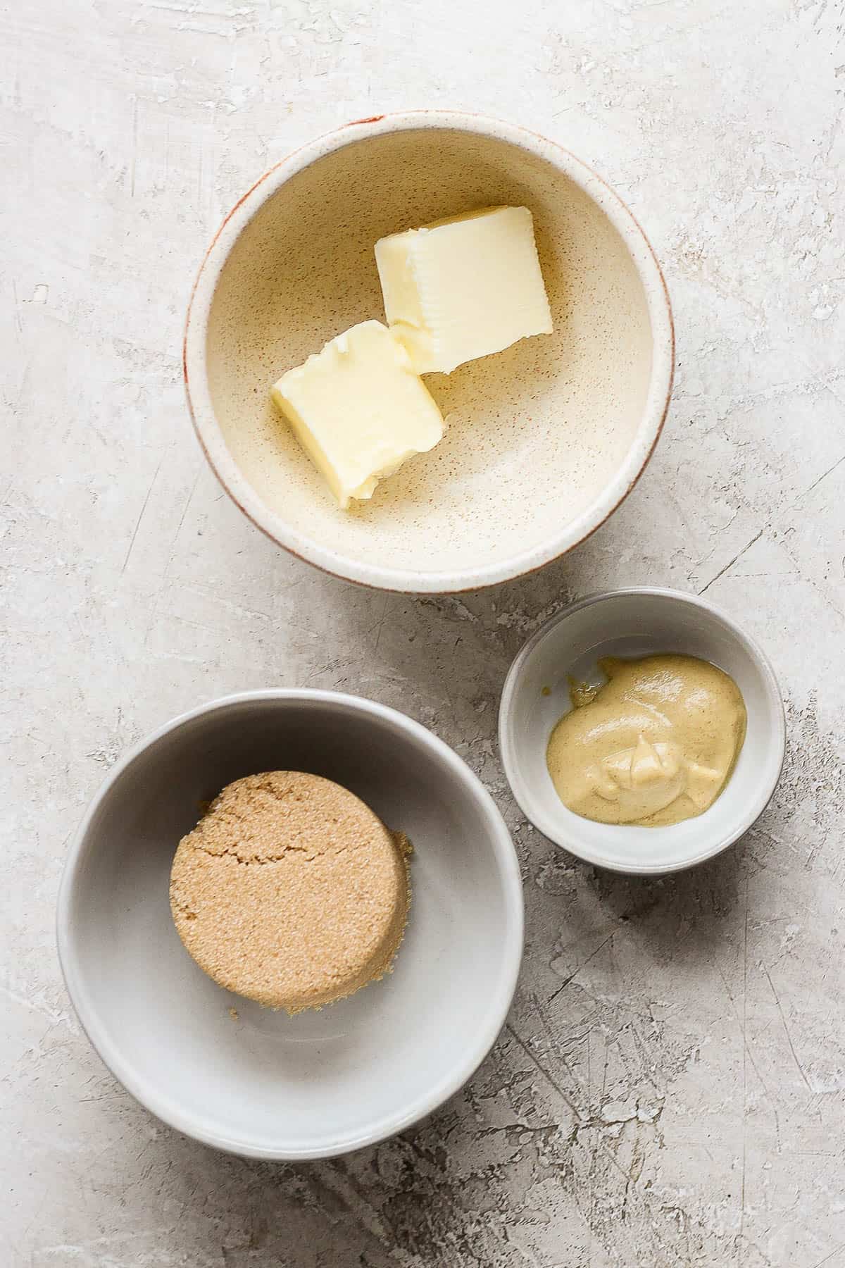 Individual bowls of butter, brown sugar, and dijon mustard.