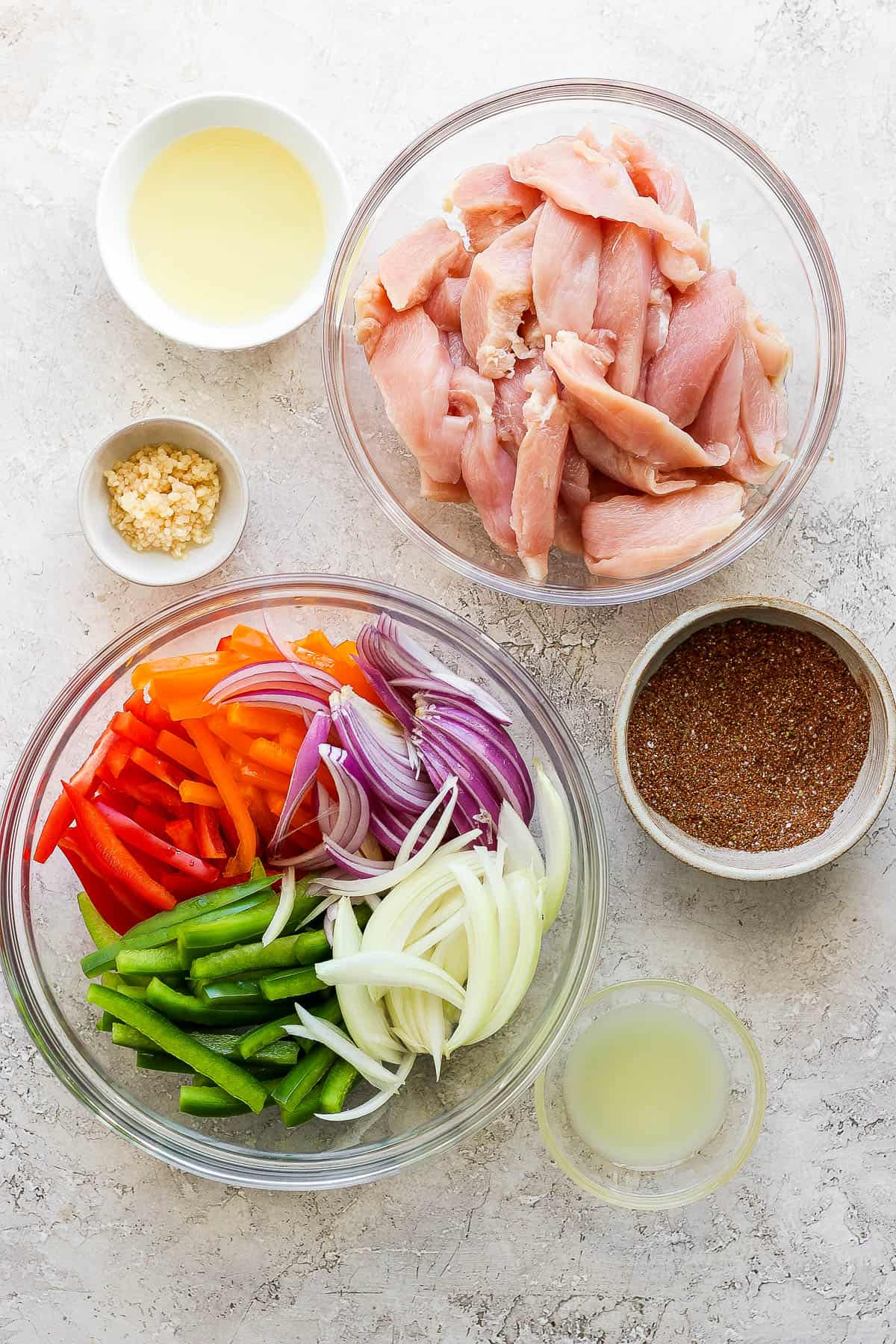 Ingredients for grilled chicken fajitas in separate bowls.
