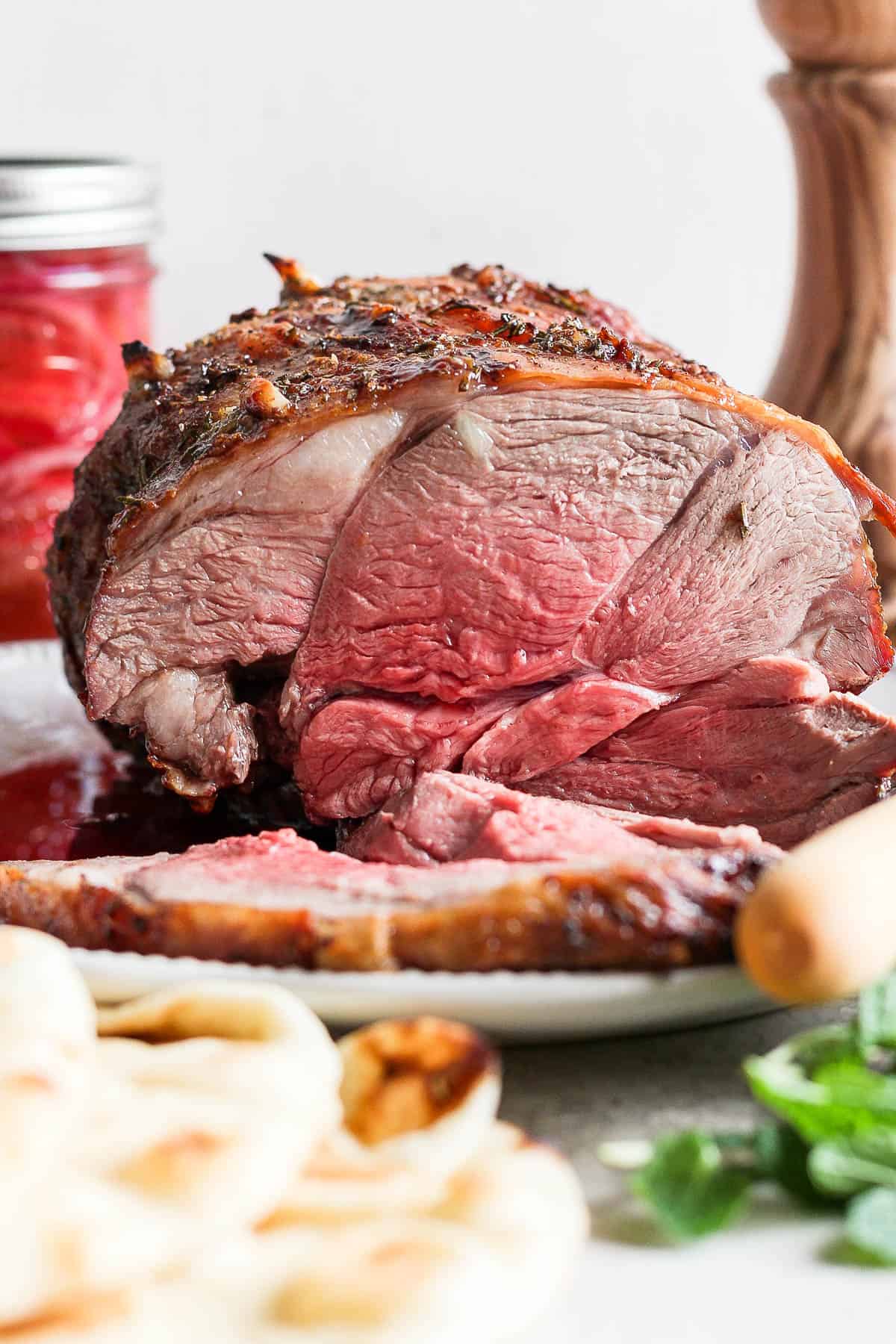 Grilled leg of lamb on a plate with slices cut off one end.