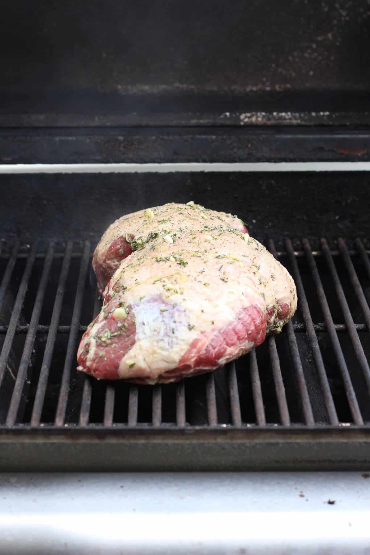 Marinated leg of lamb placed on the grill grates.