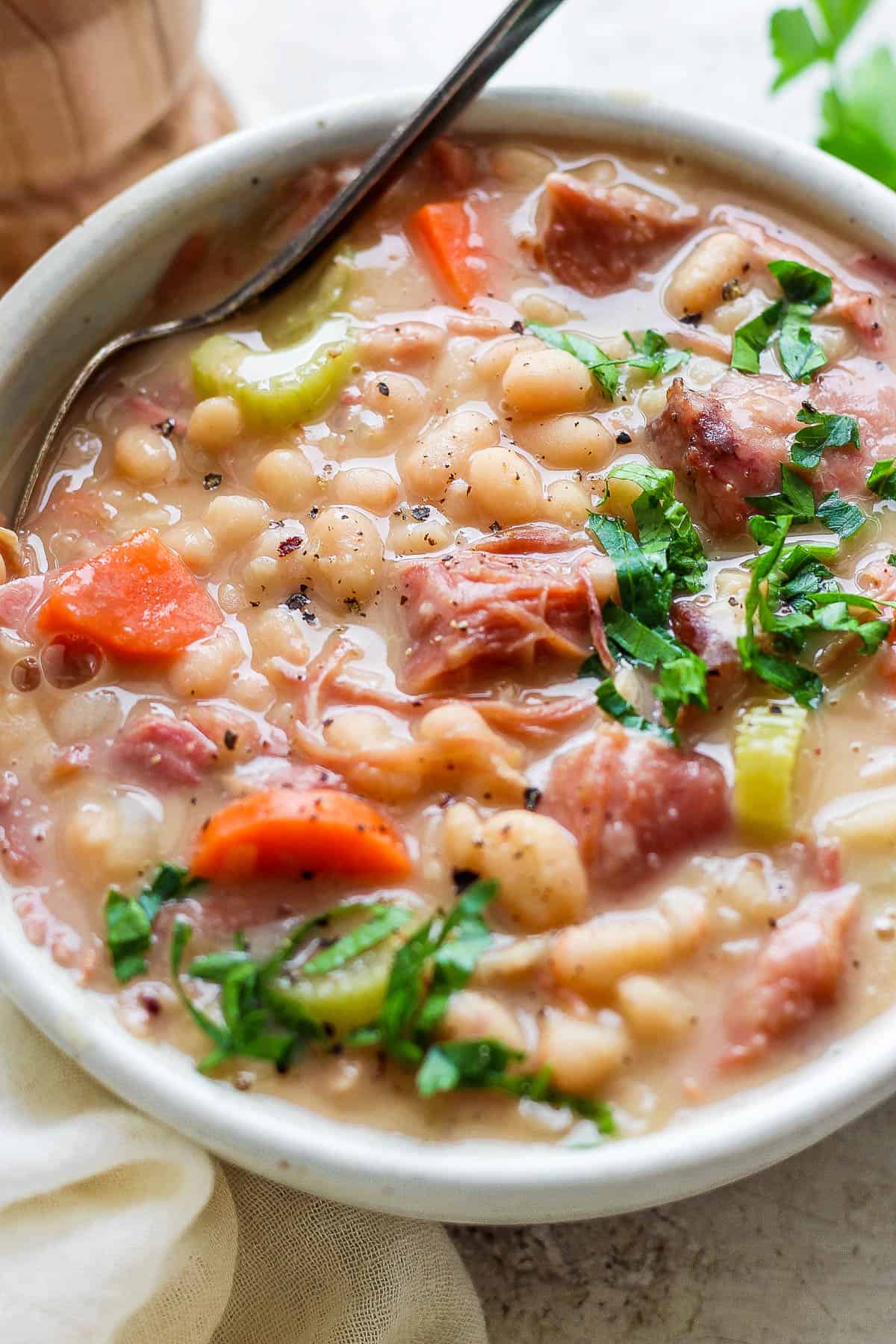 Ham bean soup in a bowl with a spoon.