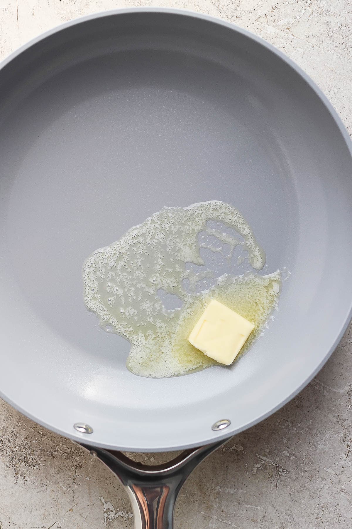 A pat of butter melting in a skillet.