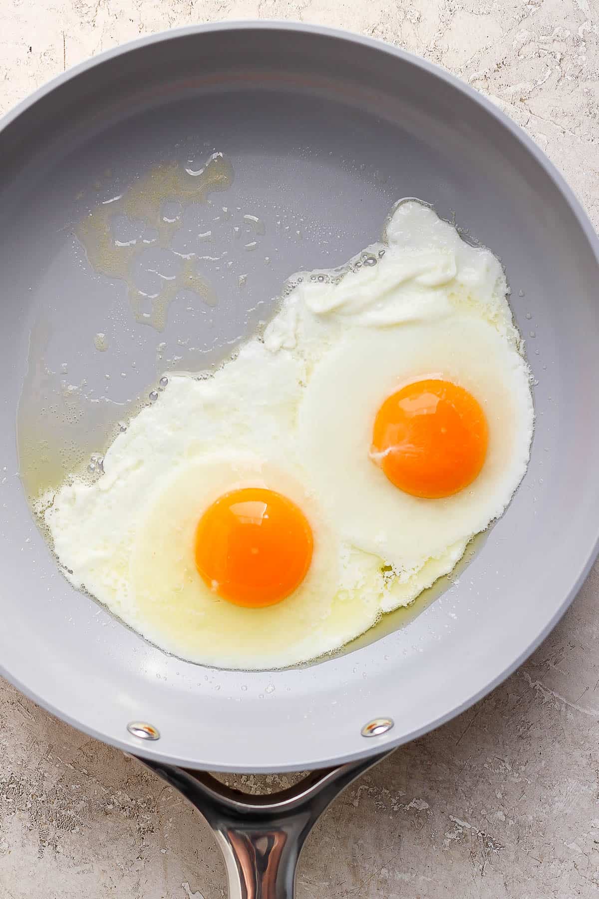 Two eggs cooking in a skillet.
