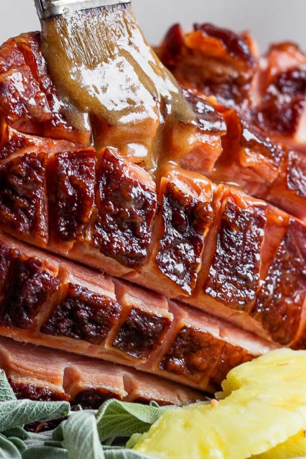 Close up shot of an Instant Pot Ham with someone brushing a glaze on top with a small brush.