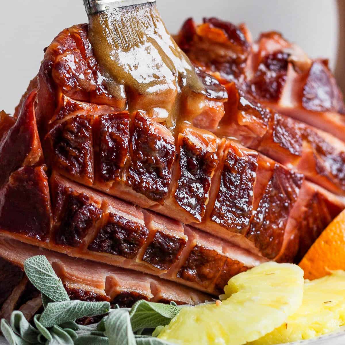 Close up shot of an Instant Pot Ham with someone brushing a glaze on top with a small brush.