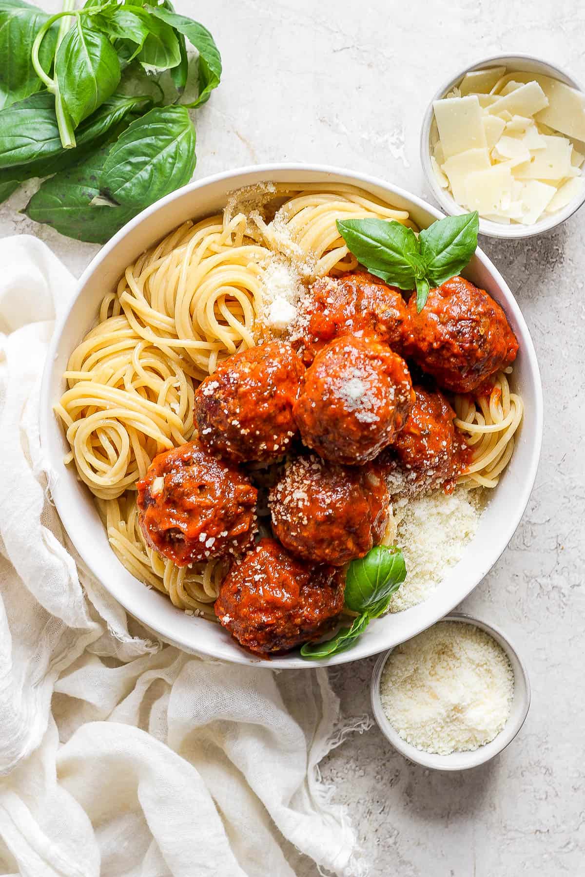 Smoked meatballs and spaghetti in a white bowl.