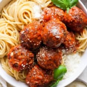 Top down shot of a bowl of spaghetti and smoked meatballs with fresh basil and parmesan cheese.
