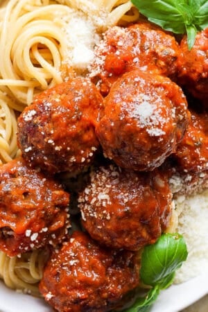 Top down shot of a bowl of spaghetti and smoked meatballs with fresh basil and parmesan cheese.