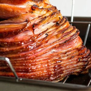 Side shot of a cooked spiral ham in a roasting pan.