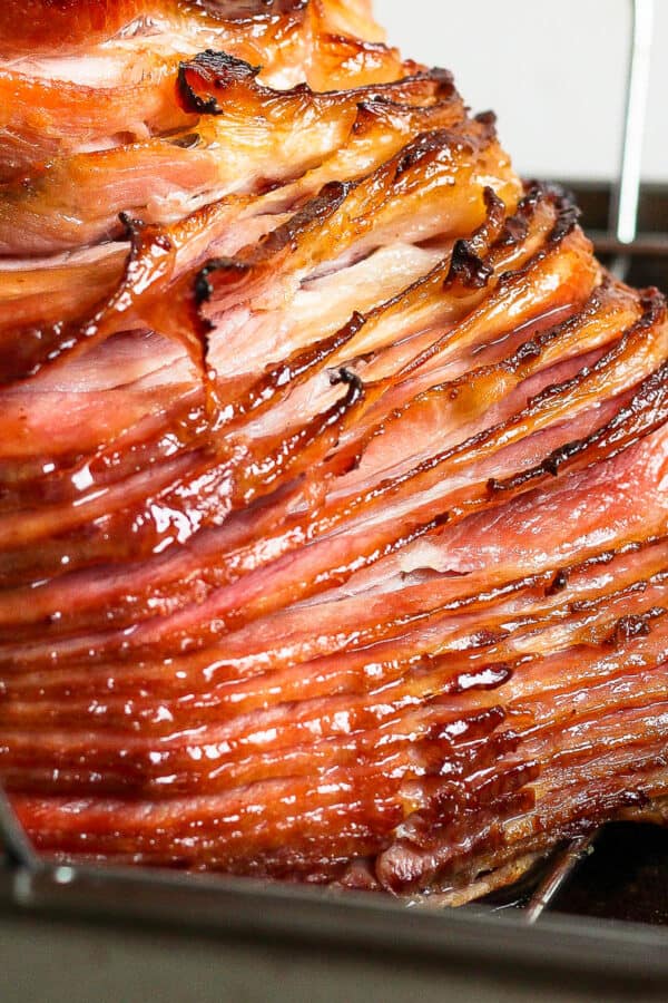 Side shot of a cooked spiral ham in a roasting pan.