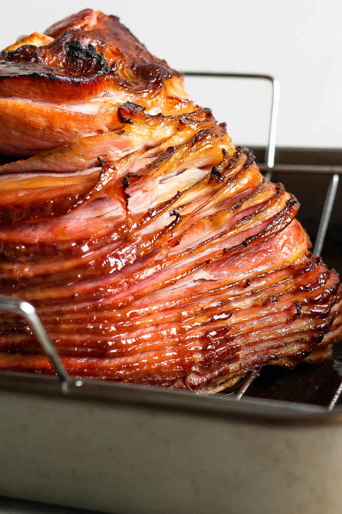A close up of a cooked spiral ham on the roasting rack.